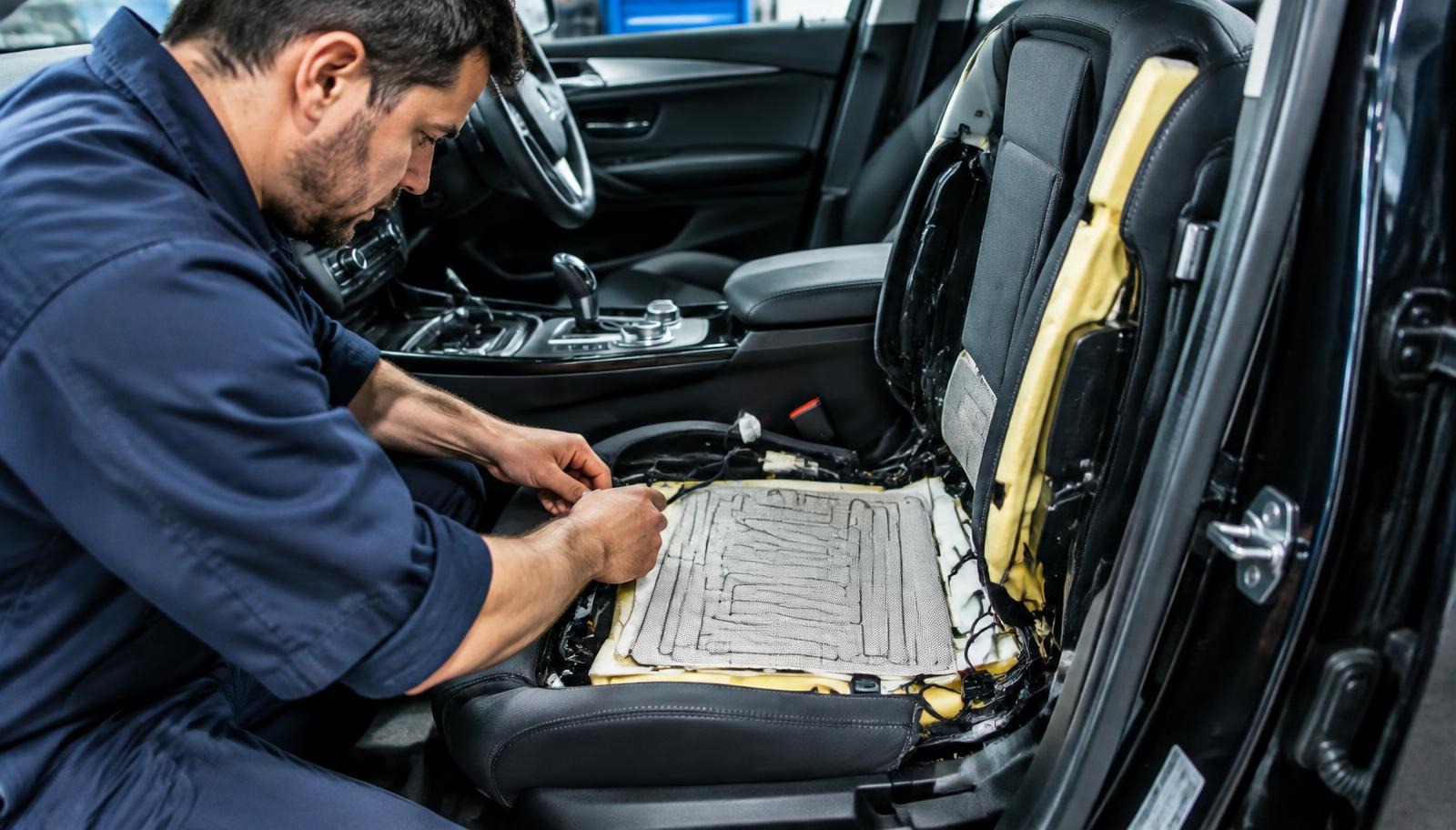 Mechanik wymieniający matę czujnika zajętości w rozebranym fotelu pasażera