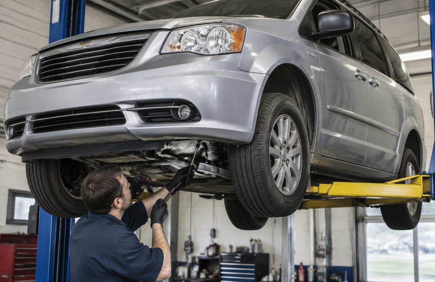 Mechanik sprawdzający przednie zawieszenie Chryslera Grand Voyager na podnośniku
