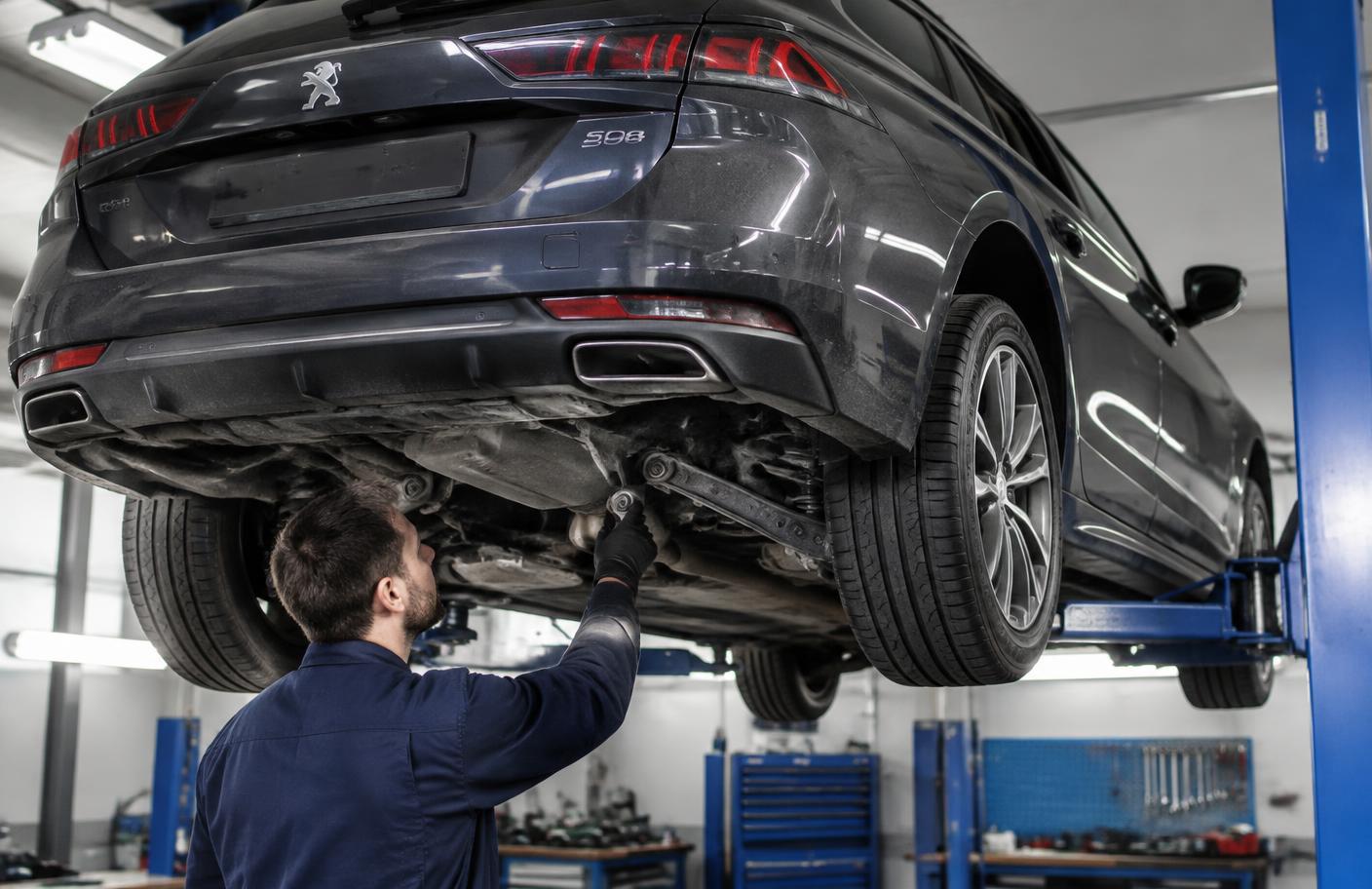 Mechanik kontrolujący tylne zawieszenie Peugeota 508 na podnośniku